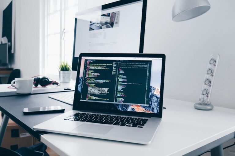 Portátil con código de desarrollo web en un escritorio blanco